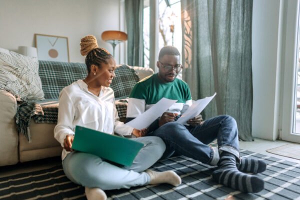 Young smiling couple going over bills while sitting on the floor at home