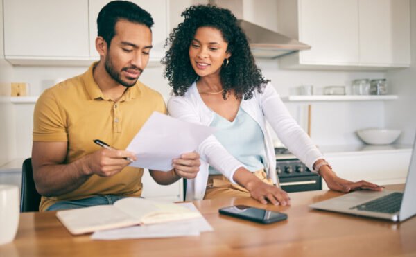 Couple, insurance paperwork and budget planning with laptop, bills and finance with taxes and mortgage. Financial documents, payment and loan with policy, audit and review with asset management